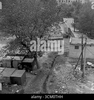 Dietro le quinte di un importante progetto di ricostruzione: Cortili interni caotici e un settore residenziale privato dietro la piazza centrale di Sloviansk, 1975-1976. Il colpo cattura vecchie case in attesa di demolizione, capannoni, detriti. Questa immagine riflette il processo di sdoganamento del sito per il rinnovamento urbano, simboleggiando un'epoca passata sacrificata per la nuova e monumentale visione di una città sovietica, e documenta la complessa ma pacifica vita nel Donbas durante quel periodo Foto Stock