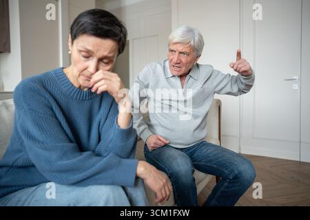 Un anziano irritato che urla e gesta una moglie triste in difficoltà, instabilità emotiva e abusi Foto Stock