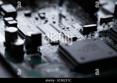 Primo piano di una scheda a circuito stampato elettronica, molti componenti complessi a montaggio superficiale. Tecnologia moderna e dinamica del futuro ed elettronica. Retroilluminato, Foto Stock
