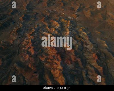 Veduta aerea dell'aspro paesaggio di Tsagaan Suvarga, con le sue impressionanti formazioni rocciose dipinte in tonalità di arancione e marrone dal tramonto, Tsag Foto Stock