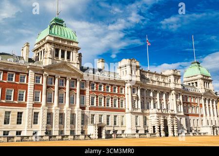 Un imponente edificio neoclassico con mattoni rossi e pietra bianca, caratterizzato da cupole verdi, colonne classiche e una bandiera Union Jack che batte contro un bri Foto Stock