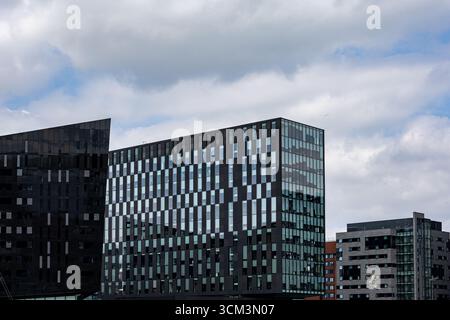 Moderni edifici in vetro e acciaio si stagliano contro un cielo nuvoloso. Gli edifici presentano motivi geometrici di pannelli e finestre scuri a Liverpool, Regno Unito. Foto Stock