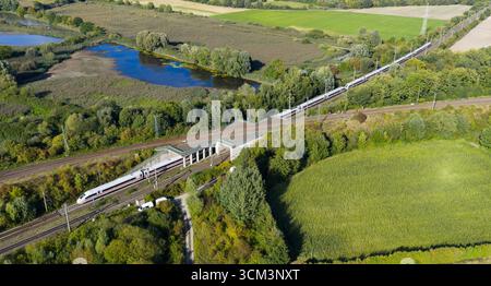 Lehrte, Germania. 14 settembre 2025. I dipendenti della Deutsche Bahn lavorano su una linea ferroviaria vicino a una scatola di segnalazione dopo un incendio sul terrapieno superiore, mentre passa un treno ICE della Deutsche Bahn da Berlino ad Hannover. A seguito di un incendio a una scatola di segnalazione, ci saranno ritardi e cancellazioni sulla linea importante tra Hannover e Berlino fino a lunedì, secondo Deutsche Bahn. Sabato, una scatola fusibili in una scatola di segnalazione a Lehrte, nella regione di Hannover, ha preso fuoco. Credito: Julian Stratenschulte/dpa/Alamy Live News Foto Stock
