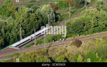 Lehrte, Germania. 14 settembre 2025. I dipendenti della Deutsche Bahn lavorano vicino a una scatola di segnalazione dopo un incendio su una linea ferroviaria come passa un treno ICE della Deutsche Bahn lento e ritardato da Berlino ad Hannover. A seguito di un incendio a una segnaletica, ci saranno ritardi e cancellazioni sull'importante rotta tra Hannover e Berlino fino a lunedì, secondo Deutsche Bahn. Sabato, una scatola fusibili in una scatola di segnalazione a Lehrte, nella regione di Hannover, ha preso fuoco. Credito: Julian Stratenschulte/dpa/Alamy Live News Foto Stock