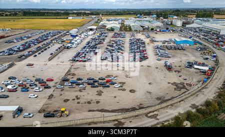 Vista aerea di un vasto deposito di veicoli pieno di automobili, camion ed edifici industriali sotto un cielo nuvoloso al cantiere Copart di York, Regno Unito. Foto Stock