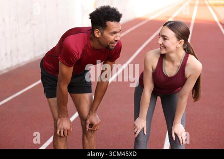 Coppia sorridente che riposa dopo corsa allo stadio Foto Stock