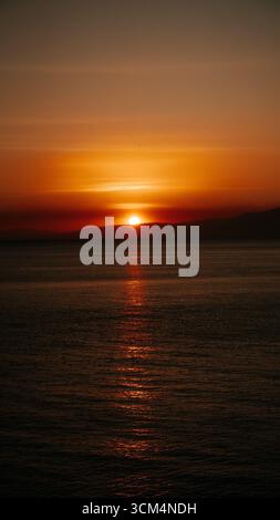 Splendido tramonto che crea una vista estetica in una combinazione di colori rosso, giallo, arancione e motivi che si affacciano sull'oceano, tranquillo e tranquillo Foto Stock