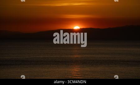Splendido tramonto che crea una vista estetica in una combinazione di colori rosso, giallo, arancione e motivi che si affacciano sull'oceano, tranquillo e tranquillo Foto Stock