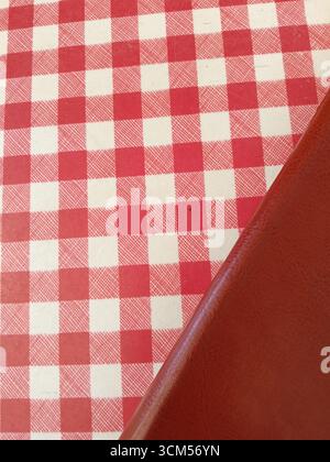 Una tovaglia a scacchi rossa e bianca è posizionata ordinatamente su un tavolo Foto Stock