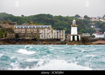 Faro Castle Breakwater e Castle Cornet sullo sfondo, visto da un traghetto che parte dal porto di St Peter in caso di maltempo, isola di Guernsey, B. Foto Stock