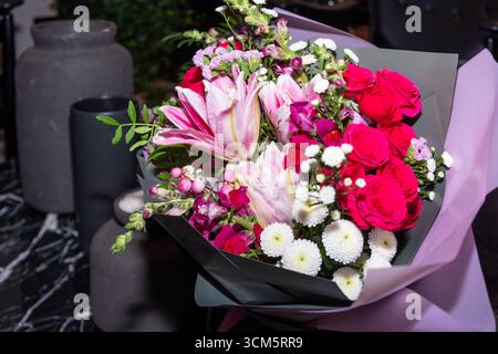 Uno splendido bouquet con rose e gigli vivaci, avvolti elegantemente, ideale per feste e regali, con una bella disposizione e invitante Foto Stock
