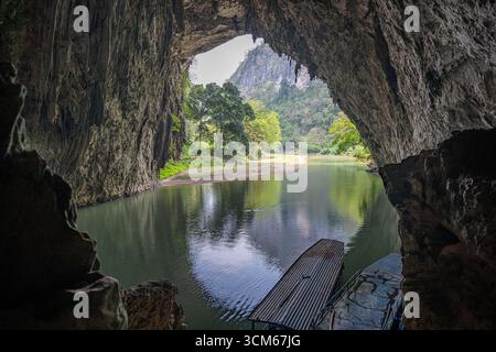 Vista dall'interno di una grotta calcarea che si affaccia su un fiume e sulle montagne lussureggianti del lago Ba Bể a Bắc Kạn, Vietnam. Foto Stock