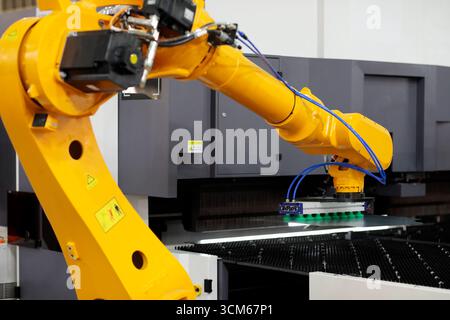 Robot che carica lamiere di acciaio nella pressa per freni. Messa a fuoco selettiva. Foto Stock