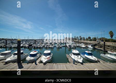 Porticciolo di Mazagón, con barche di varie dimensioni ormeggiate in una giornata di sole con acque calme e frangiflutti circostanti. Foto Stock