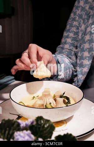 Gustosi bocconcini in un brodo cremoso che delizia e sono gustati da una mano di Diners Foto Stock