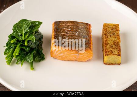 Filetto di salmone scottato servito con spinaci saltati e croquette di patate Foto Stock