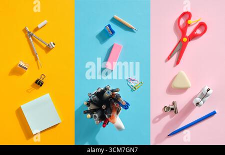 Disposizione vivace di articoli di cancelleria, tra cui forbici, penne e graffette, visualizzati su uno sfondo a tre colori per un'ispirazione creativa Foto Stock