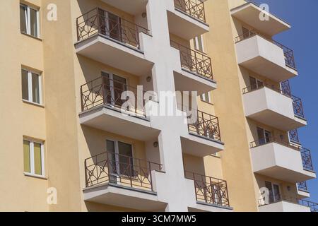 Facciata di un edificio a più piani in costruzione illuminato dal sole. Costruzione Foto Stock