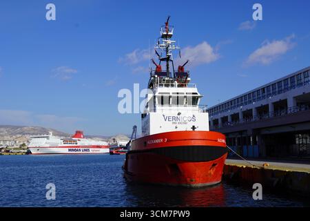 1° gennaio 2024, Pireo, Grecia. Un rimorchiatore rosso e un traghetto, nel porto Foto Stock