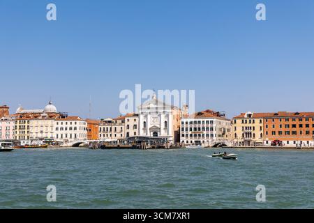 Venezia, Italia, 11 agosto 2025: Lungomare veneziano con chiesa ed edifici colorati Foto Stock