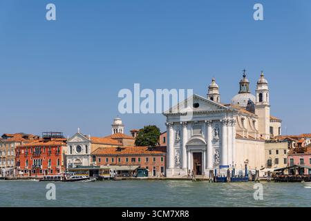 Venezia, Italia, 11 agosto 2025: Lungomare veneziano con chiesa storica e cupola Foto Stock