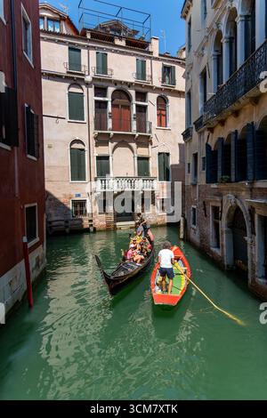 Venezia, Italia, 11 agosto 2025: Gondola e barca a remi nello stretto canale di Venezia Foto Stock