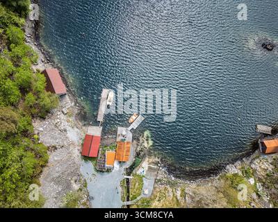 Una vista ad alto angolo che cattura piccoli moli, barche e vivaci barche lungo una costa panoramica. Foto Stock