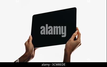 Due mani che reggono un tablet digitale moderno e vuoto, isolato su uno sfondo bianco. L'immagine suggerisce temi di tecnologia, connettività e po Foto Stock