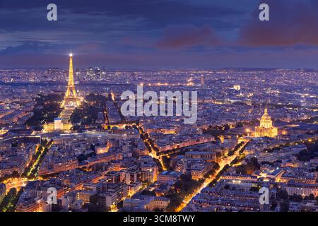 Vista serale elevata della Torre Eiffel, Les Invalides e dello skyline di la Defense illuminato al crepuscolo sui tetti di Parigi Foto Stock