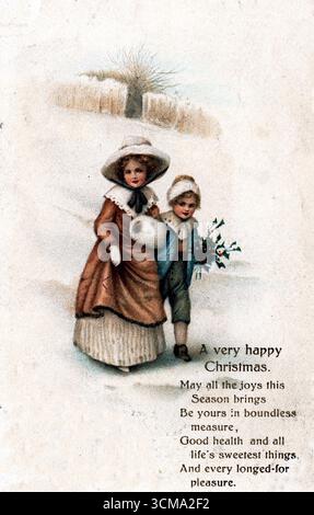 Due bambini camminano braccio in braccio attraverso un campo innevato, uno porta una grande brocca bianca, l'altro un ramoscello di holly. Indossati con abiti invernali marroni e blu con cofani, passano davanti a un pagliaio o a un cespuglio. Un messaggio poetico sopra offre desideri di gioia e salute. Pubblicato da AMAG (Albrecht & Meister, Berlino), questo biglietto irradia calore rustico. Da un biglietto di auguri edoardiano originale. Foto Stock
