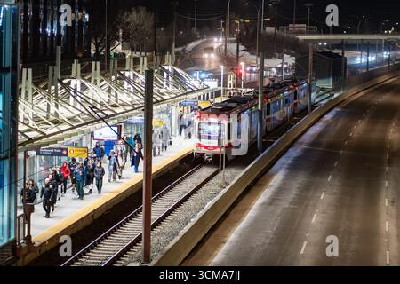 Calgary, Alberta Canada, 20 aprile 2025: I pendolari lasciano un treno leggero che cammina lungo una piattaforma in prima serata. Foto Stock