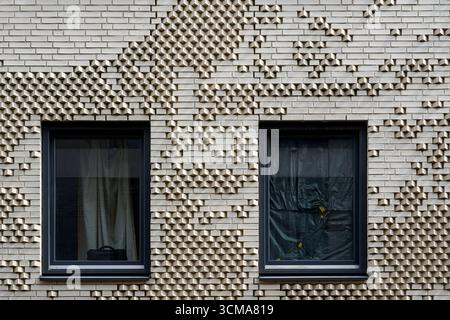 Motivi testurizzati: Ritmi urbani. Due finestre di un edificio residenziale a Eindhoven, Paesi Bassi, sono incorniciate da intricati mattoni che formano ritmi geometrici. Foto Stock