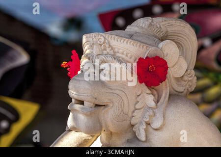 il dio delle scimmie Hanuman scolpito in pietra con fiori di ibisco rosso, pietra calcarea bianca, Hanuman, induismo, indù, Ubud, Bali, Indonesia, Asia, Europa, antenna Foto Stock