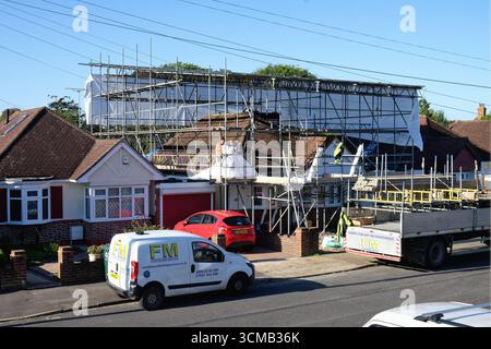 Scaffolders che erigono una copertura impermeabile su un bungalow periferico prima che vengano eseguiti importanti lavori di costruzione, Shepperton, Surrey, Inghilterra Foto Stock