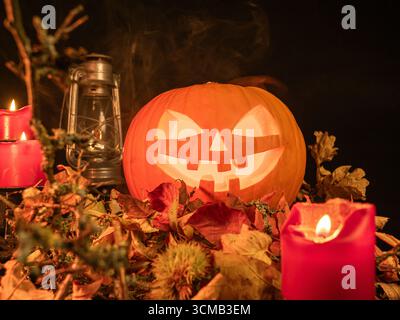 Jack-o'-lanterna luminosa con candele rosse e foglie d'autunno per la notte di Halloween. Foto Stock