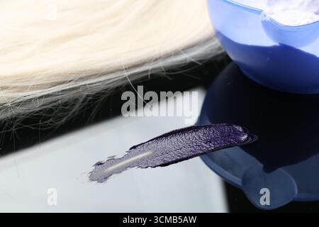 Prodotto cosmetico per la cura dei capelli, lucchetto biondo e polvere sulla superficie dello specchio, primo piano Foto Stock