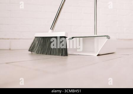 Set elegante bianco per pulire la casa, la scopa e la paletta da vicino su sfondo bianco. Foto Stock