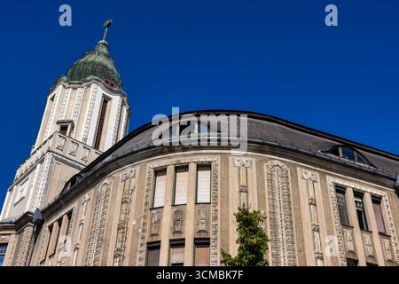 Debrecen, Ungheria 30 luglio 2025 - edificio storico ornato con scolpite in pietra, torre a cupola e facciata curva sotto un cielo blu vivace. Foto Stock