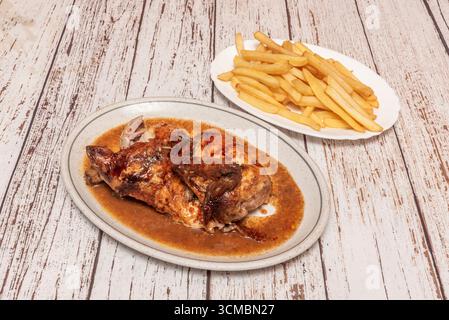 Pollo arrosto in stile greco con limone e origano, accompagnato da patatine fritte con feta sbriciolata e olive Foto Stock