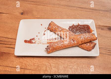 Crepes di cioccolato con un tocco di arancia ripiene di crema al cioccolato allo zenzero, decorate con scorza di agrumi candita Foto Stock
