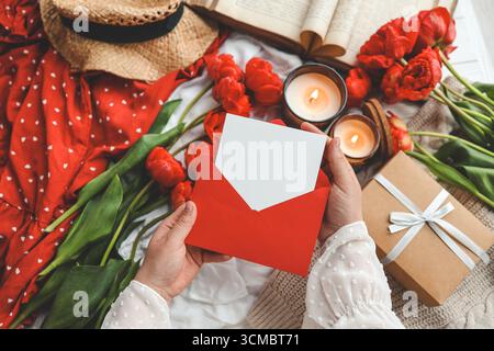 Le mani di una donna che tiene una lettera in una busta di artigianato. Festa della mamma o San Valentino. Inserire il testo. Foto Stock