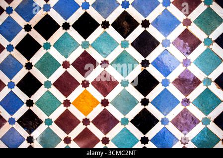 Il motivo geometrico delle piastrelle mette in mostra colori vivaci e disegni complessi, con quadrati e diamanti in varie tonalità, creando un decoro accattivante Foto Stock
