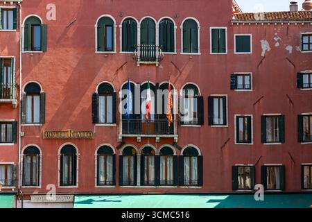 Venezia, Italia, 11 agosto 2025: Facciata dell'hotel Rialto con bandiere europee e italiane Foto Stock