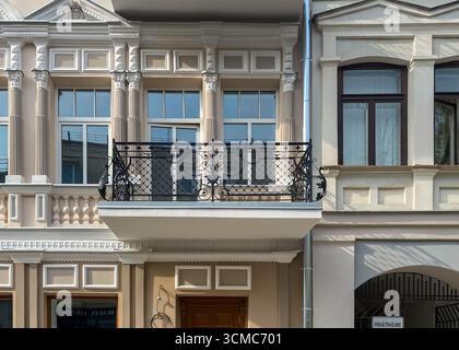 Ringhiera per balcone in ferro battuto. Facciata ristrutturata e decorata della casa storica con balcone decorativo in ferro in stile retrò. Appartamenti immobiliari Foto Stock