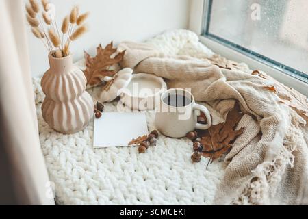 Tazza di tè, candela, plaid e foglie nell'interno della casa autunnale. Foto Stock