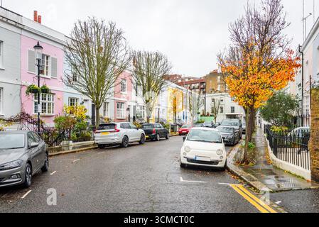Case terrazzate in mattoni color pastello lungo una strada in una giornata di pioggia Foto Stock