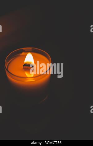 Candela che brucia nel primo piano scuro. Foto Stock