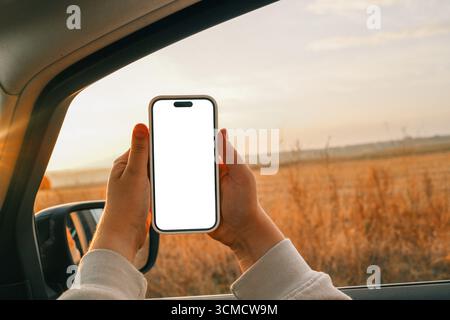 Telefono in mano con schermo isolato sullo sfondo di una strada autunnale. Foto Stock