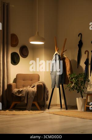 Poltrona, appendiabiti e lampada a incandescenza all'interno del corridoio Foto Stock