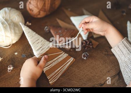 Il bambino fa decorazioni natalizie con filati. Foto Stock